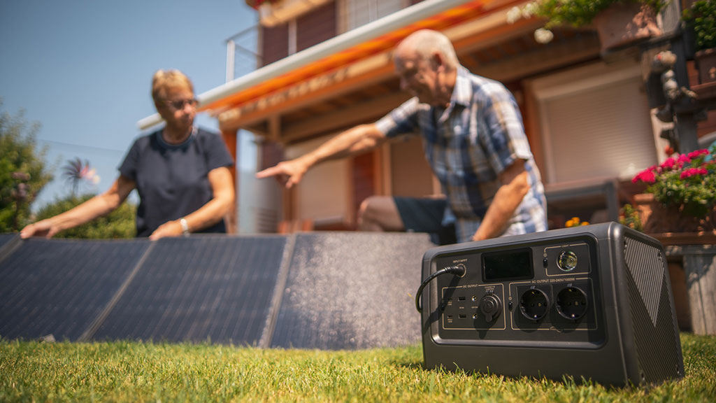 Portable solar generator and panels in garden, owners blurred in background